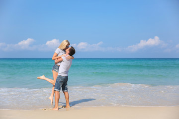 Fototapeta na wymiar Young happy couple on beach smiling holding around each other. Love story