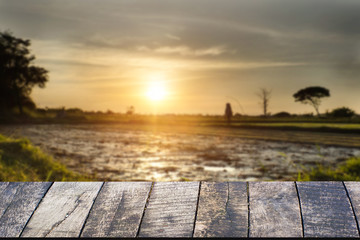 Fototapeta na wymiar Empty of wooden desk space platform and empty Agriculture field and sunset vintage tone.