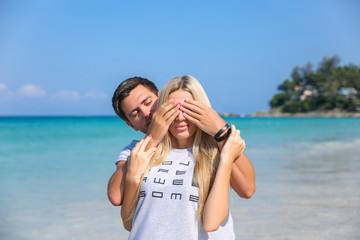 Outdoor closeup portrait of pretty young couple in love having fun in hot weather and feeling happy together on the tropical island. Posing and hugs alone on the beach.