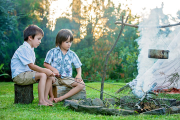 Naklejka na ściany i meble Two sweet children, boy brothers, camping outside summertime on sunset