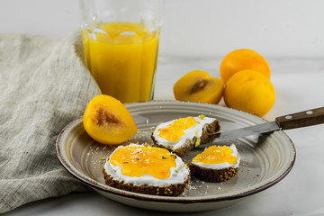 Sandwich with apricot jam and cottage cheese on a white plate, end with copy space