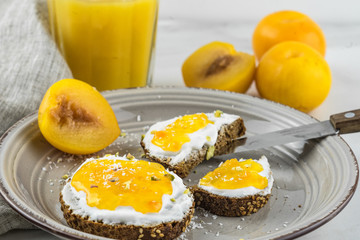 Sandwich with apricot jam and cottage cheese on a white plate, end with copy space