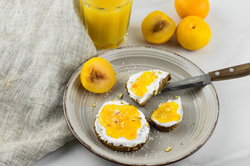 Sandwich with apricot jam and cottage cheese on a white plate, end with copy space