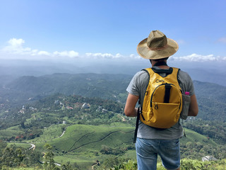 Young caucasian male traveling backpacker up hill and down dale in Munnar, Kerala state, Idukki...