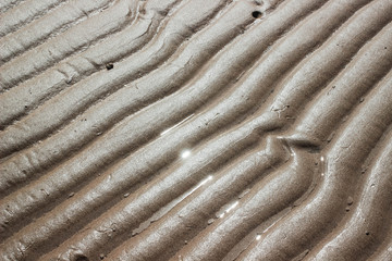 Ripple sand on the beach after low tide with sunlight reflection