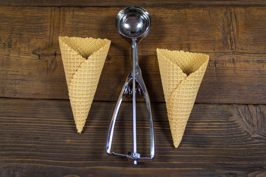 Cornets and spoon for ice cream on wooden background
