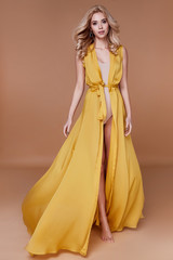 Blond hair woman beautiful face sexy skinny body shape tan skin care wear fashion dress silk yellow...