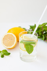 Homemade lemonade with water, lemon and mint leaves in a glass on a white background.