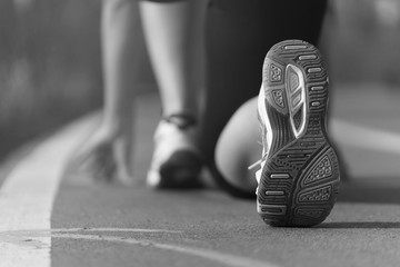 Athlete runner feet running in the Park on the track closeup on shoe, white and black