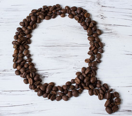 .Q letter of the English alphabet made of coffee beans. Light, old wooden background. Selective focus..