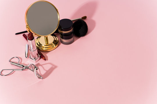 make up products and tools on pink background