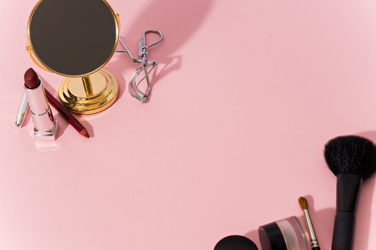 make up products and tools on pink background