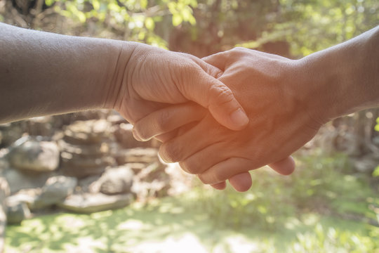 hands shake over nature background