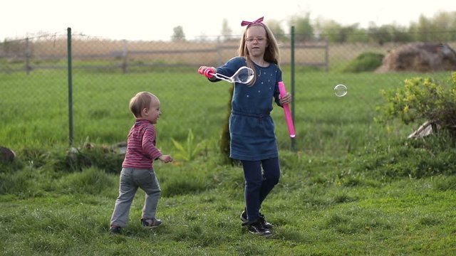 Happy cute children playing with bubbles in yard