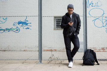 Modern young man listening to music with mobile phone in the street.