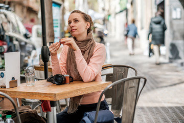 Woman with camera in outdoor cafe. Barcelona, Catalonia.
