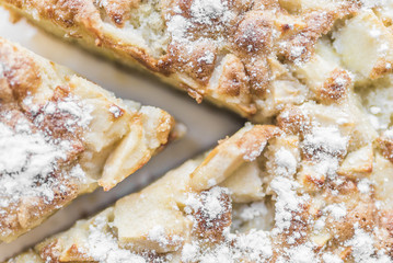 Apple pie and a cut piece of pie with powdered sugar close-up