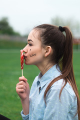 Beautiful and happy girl in the blue shirt with lollipop stadium