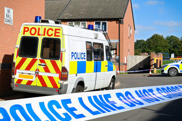 British Police vehicles at cordoned off crime scene in a typical English town
