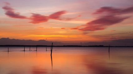 Fototapeta na wymiar beautiful clouds sunrise over water with a fike