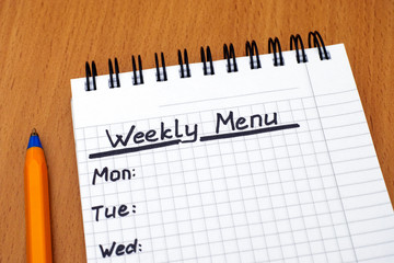 Words Weekly Menu written on white note pad with pen