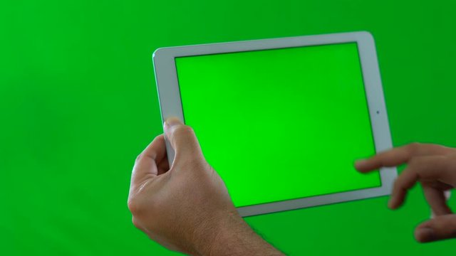 4k Man using tablet device against green screen.