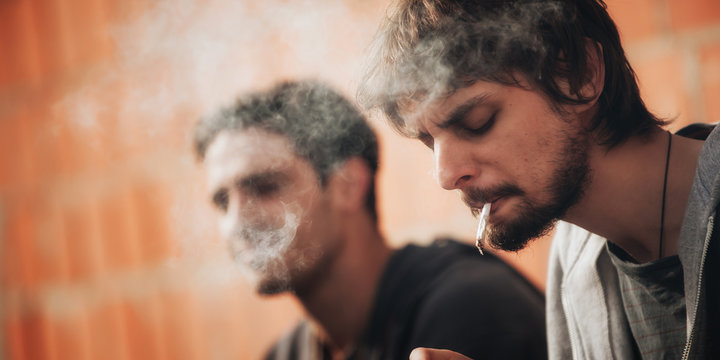 Closeup of friends smoke pot or hashish joint in ghetto