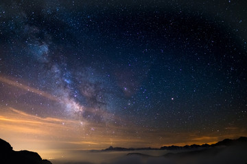 Naklejka premium The colorful glowing core of the Milky Way and the starry sky captured at high altitude in summertime on the Italian Alps, Torino Province. Mars and Saturn glowing mid frame.