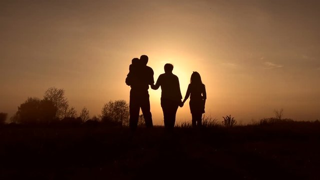 Family silhouettes on spirng sunset in the meadow