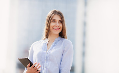 Portrait of pretty businesswoman in smart casual using digital tablet outdoors. copy space