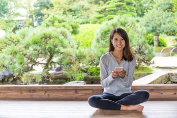 Woman using cellphone and sitting at wooden floor