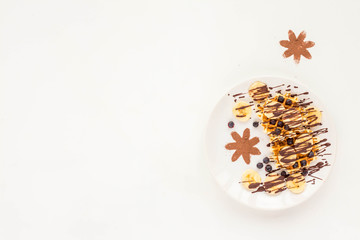 Breakfast with pate of belgian waffles with fresh fruit, chocolate, banana, berry, blueberries, on white background. Flat lay, top view, mock up
