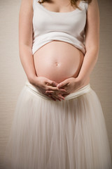 Closeup of young pregnant woman's belly. Expecting a baby. Motherhood and childhood.