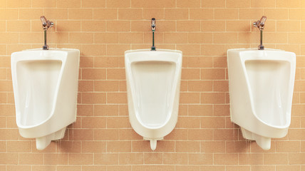 Row of white urinal for men on tile wall in toilet.