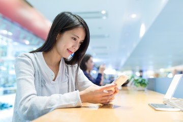 Woman using cellphone in coffee shop