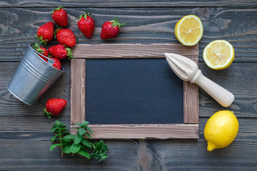 Ingredients for homemade strawberry lemonade on wooden table, around chalk board, top view, copy space