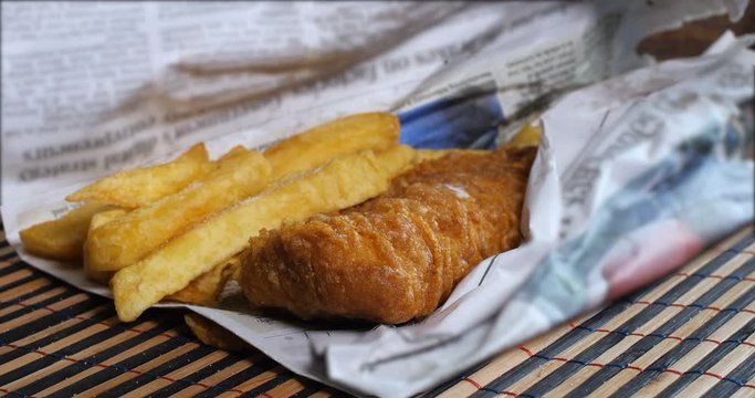 Adding salt and vinager on an Enlish fish and chips wrapped in newspaper, the traditional way
