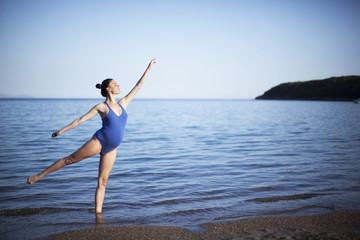 Beautiful young pregnant ballerina dancing on the beach