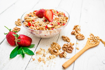 Oatmeal porridge with blueberries, strawberries and muesli on white wood background. Top view. Diet breakfast.