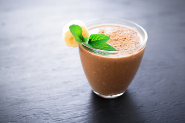 Chocolate banana smoothie on dark background. Fresh milkshake and mint