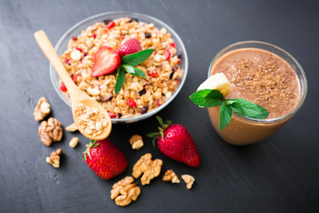 Oatmeal porridge with blueberries, strawberries and muesli on wooden background. Chocolate banana smoothie. Top view. Diet breakfast.