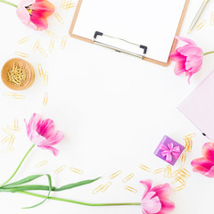 Home office table desk frame with clipboard, notebook, pink flowers and accessories on white background. Flat lay, top view. Office workspace