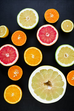 Citrus fruits on dark background. Flat lay, top view. Tropical summer mix grapefruit, orange, mandarin, lime