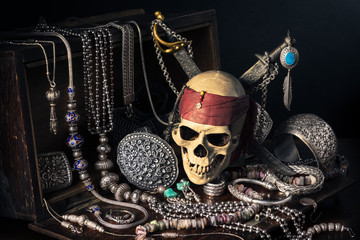 still life photography : pirate skull with two swords and treasure coffer of silver jewelry,...