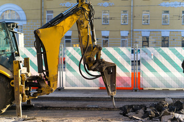 An excavator-mounted hydraulic jackhammer being used to break up concrete.