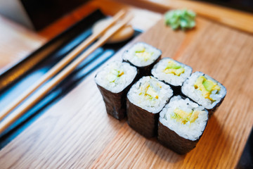 Rolls in nori seaweed with avocado, pickled ginger and soy sauce. Asian cuisine, traditional dish - sushi.