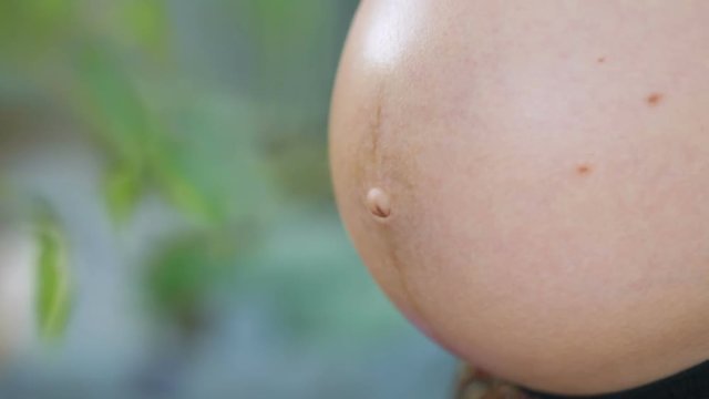 Young pregnant women caress her belly with children in the garden