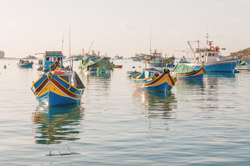 Fototapeta premium Mediterranean traditional colorful boats luzzu. Fisherman village in the south east of Malta. Early winter morning in Marsaxlokk, Malta.