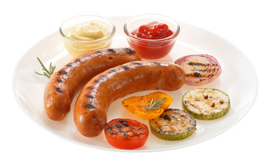 Sausages grilled with vegetables and sauce on the plate. Isolated on white background.