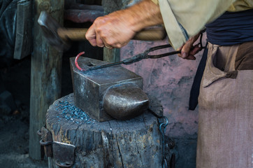 Closeup of a blacksmith's hands hammering iron on an anvil. 